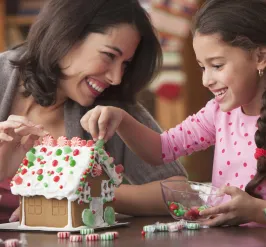 mom and daughter building a gingerbread house
