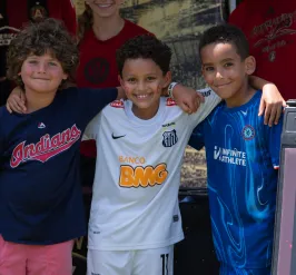 3 kids with their arms around each other smiling