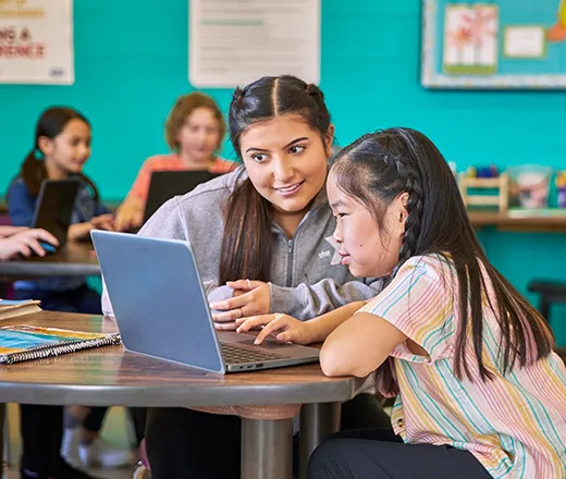 YMCA teacher helping student on laptop