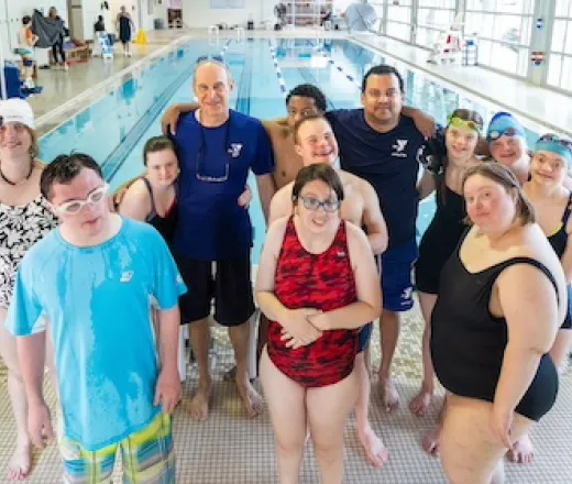 a group photo of adaptive swim participants with the pool in the background