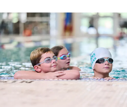 3 swimmers at the edge of the pool